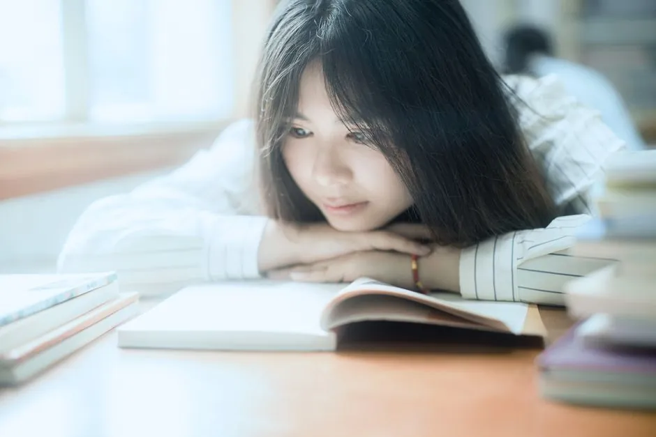 A young woman reading a book indoors, in soft natural light, creating a serene study atmosphere.