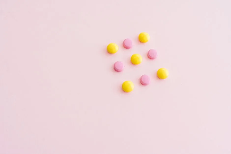 Vibrant yellow and pink pills arranged on a pink surface, offering ample copy space. Perfect for health themes.