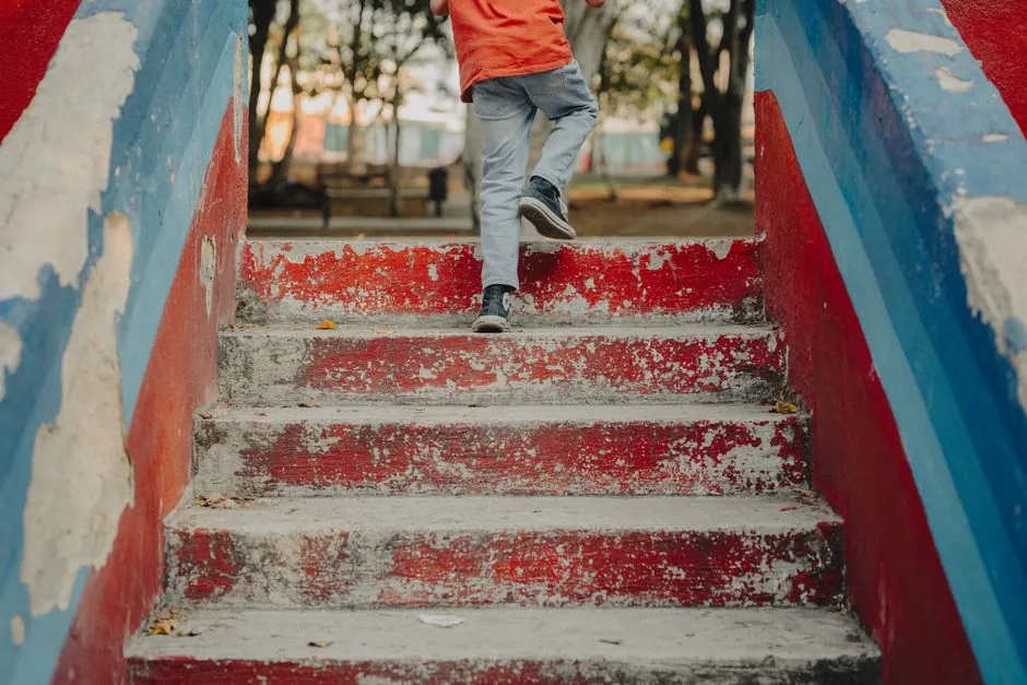 Young child climbing colorful, weathered stairs in a park setting.