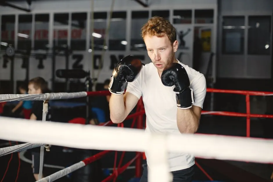 Focused boxer practicing punches in a well-lit indoor gym boxing ring.