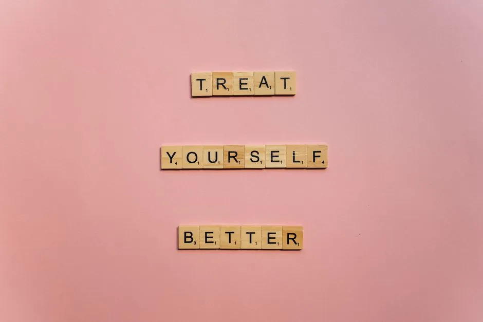 Wooden tiles on a pink background spelling 'Treat Yourself Better'. Ideal for self-care and motivation themes.