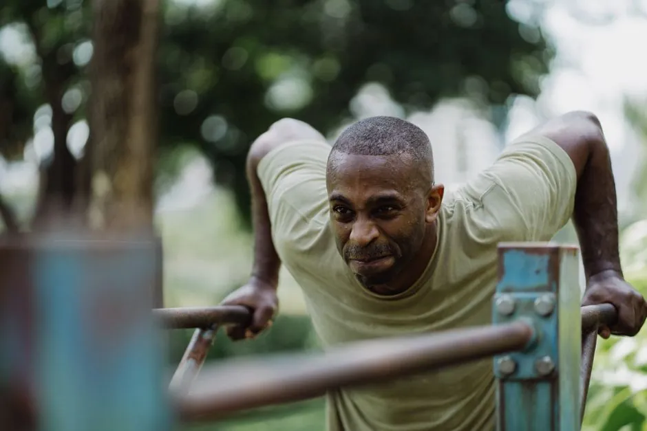 A determined man engaged in outdoor exercise dips on a sunny day.