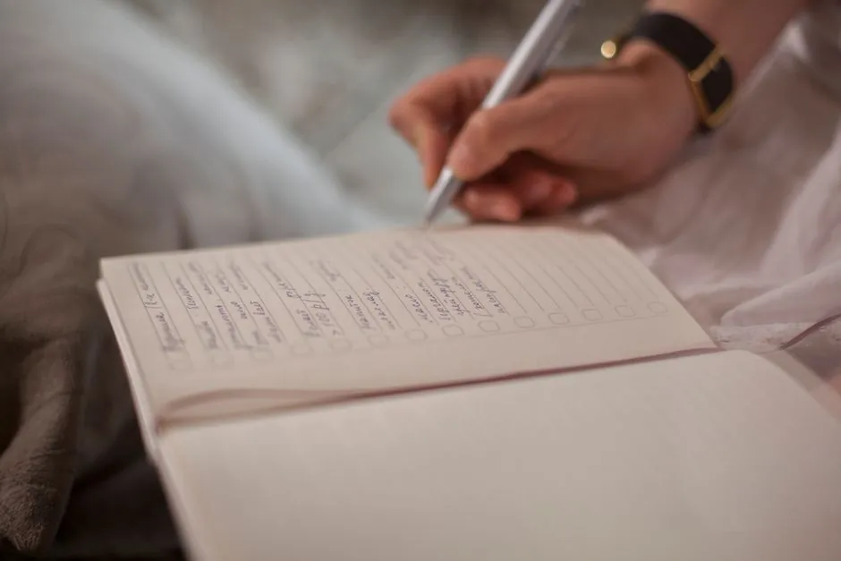 A close-up image of a person's hand writing in a notebook, emphasizing focus and creativity.