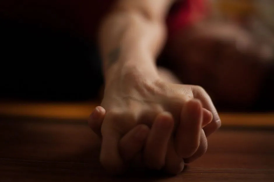 A close-up shot of two hands clasped together on a wooden surface, conveying intimacy and connection.
