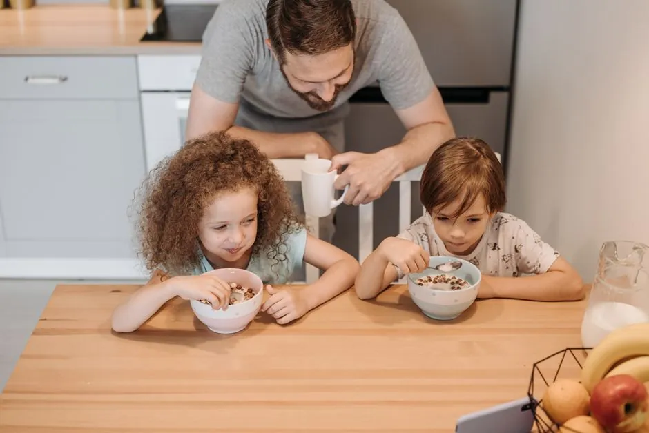 Father and children enjoying a hearty breakfast at home, creating a warm family moment.